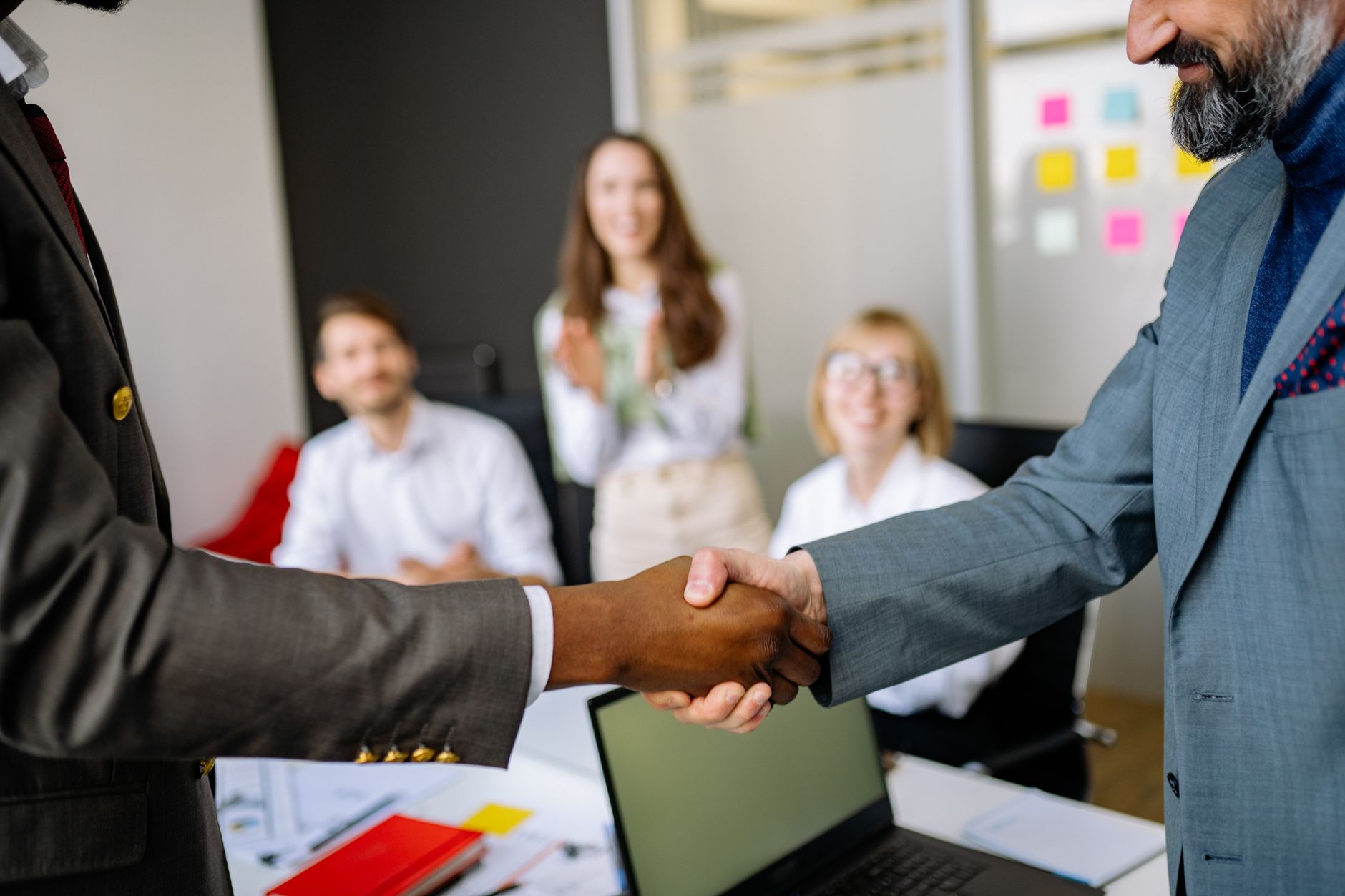 Two business professionals shaking hands over a signed contract representing a corporate operator deal