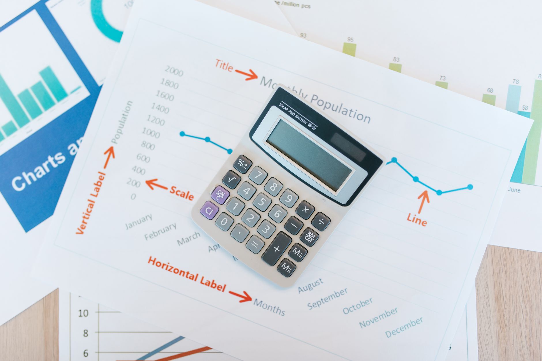 Business analyst reviewing financial performance charts on a desk with printed reports