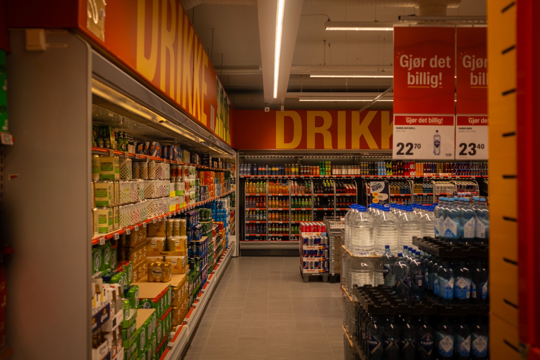 Wide supermarket aisle with product shelves stretching into the distance