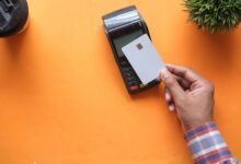 A customer tapping a debit card on a contactless payment terminal at a retail checkout counter