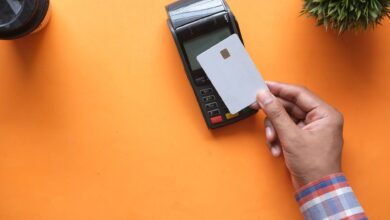 A customer tapping a debit card on a contactless payment terminal at a retail checkout counter