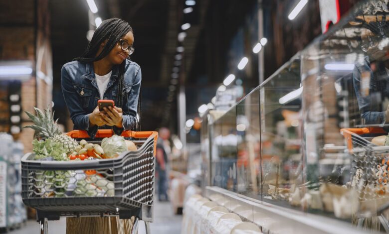 Person pushing a grocery cart through a supermarket aisle