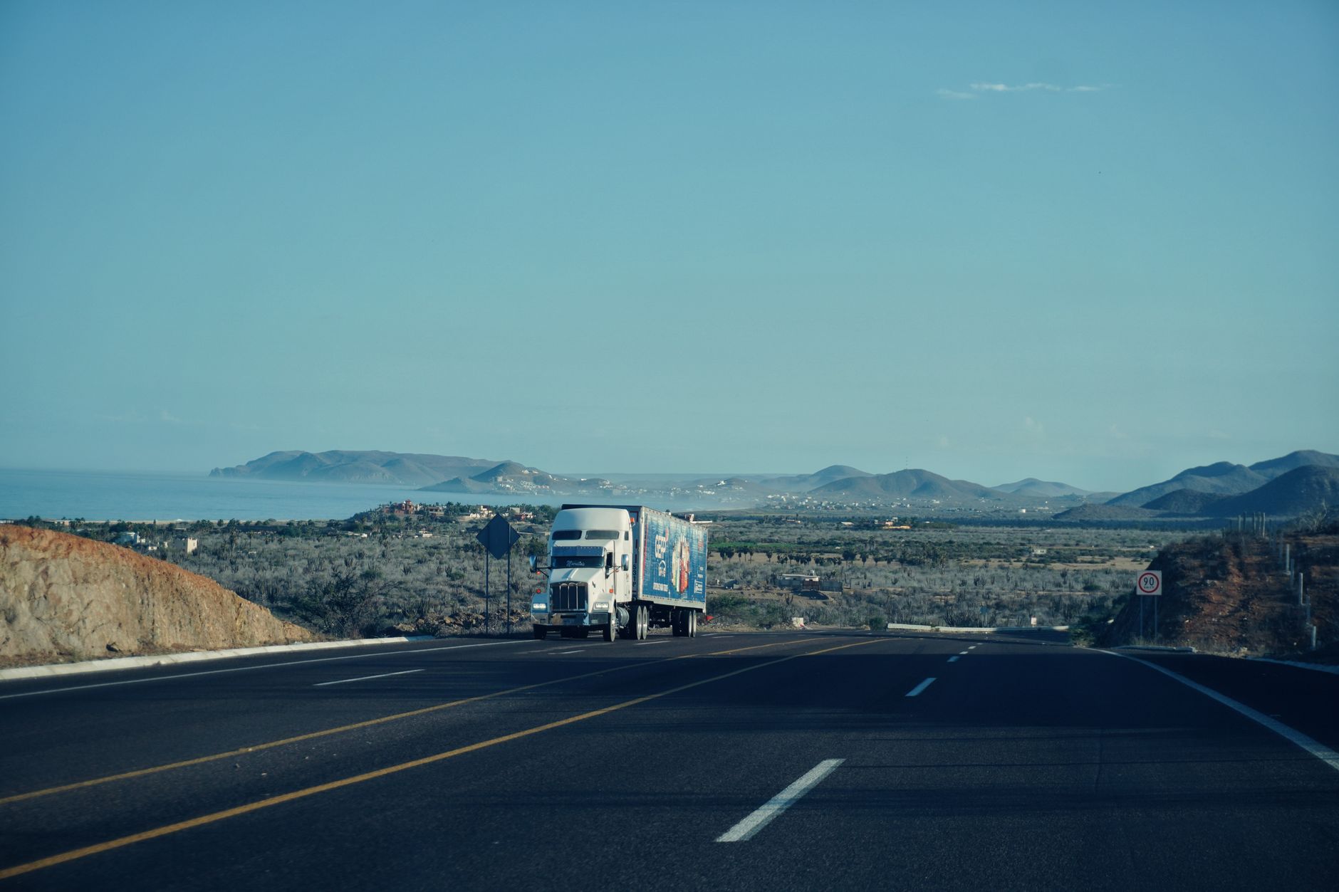 A semi-truck driving along an open highway representing freight logistics and trucking industry