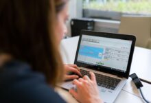 Designer working on a laptop with design software open on screen