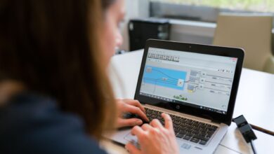 Designer working on a laptop with design software open on screen