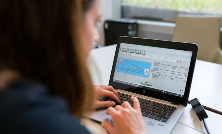 Designer working on a laptop with design software open on screen