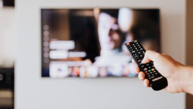 Person holding a television remote control while watching cable TV at home