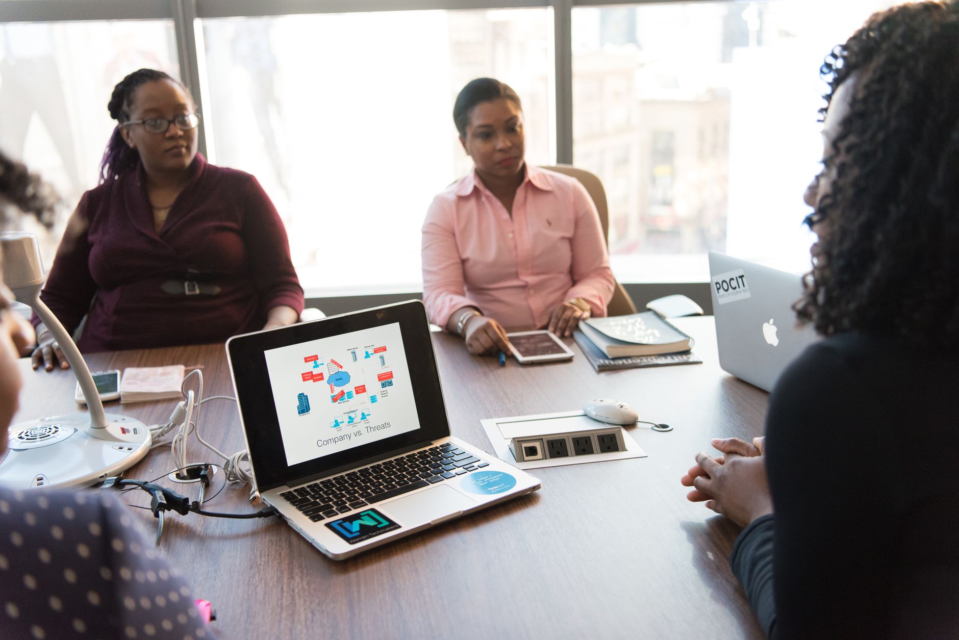 Professionals reviewing design work on laptops in a modern office meeting