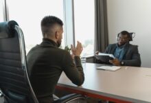 A recruiter reviewing candidate profiles on a laptop in a modern office environment