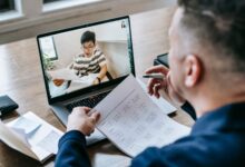Professional using video conferencing software on a laptop in a modern office setting