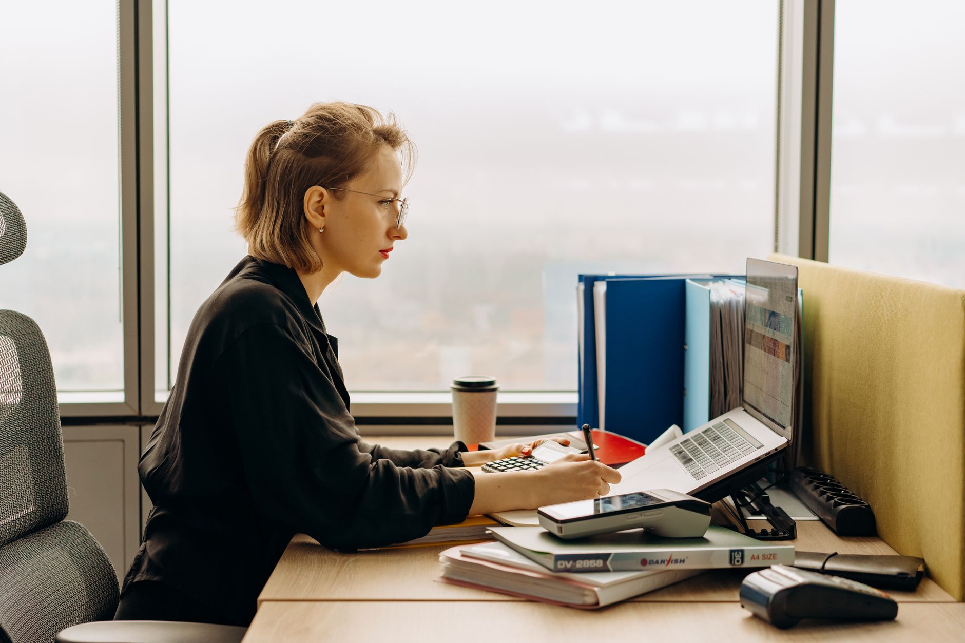 A person using accounting software on a laptop at a small business desk