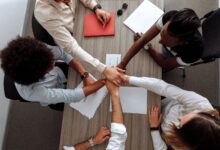 A team of colleagues collaborating around a shared screen in a modern office workspace