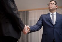 Two business executives reviewing documents at a conference table during a high-stakes negotiation