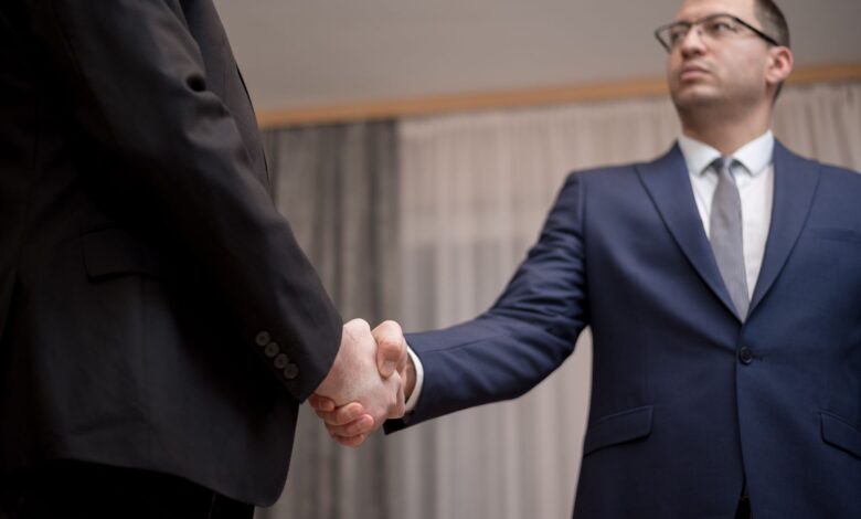 Two business executives reviewing documents at a conference table during a high-stakes negotiation
