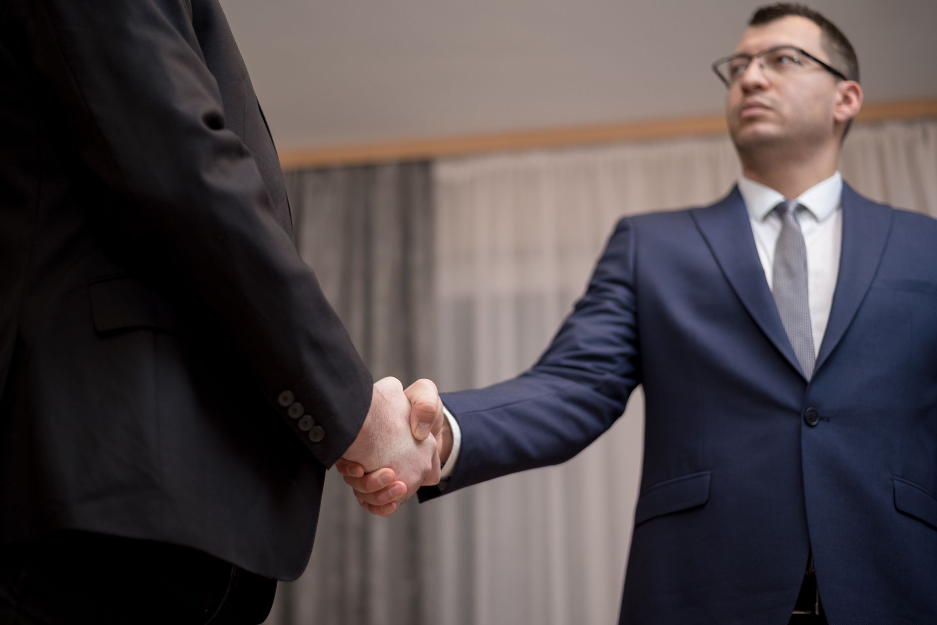 Two business executives reviewing documents at a conference table during a high-stakes negotiation