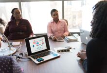 Business professionals in a modern office discussing technology tools on a laptop screen