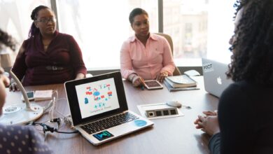 Business professionals in a modern office discussing technology tools on a laptop screen