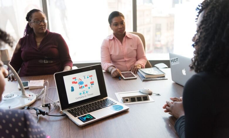 Business professionals in a modern office discussing technology tools on a laptop screen