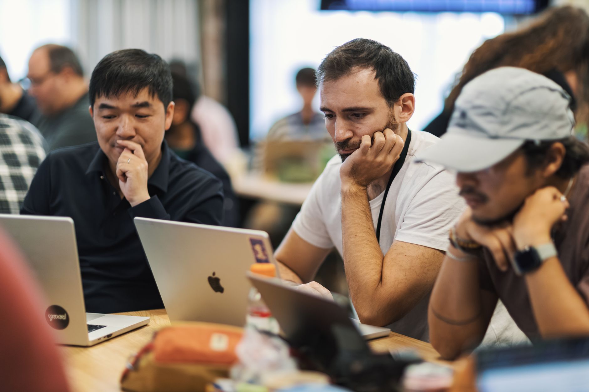 Software development team collaborating around a project management dashboard on a large monitor