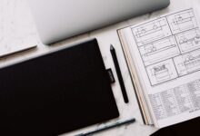 A professional designer working on a laptop with design software open on screen