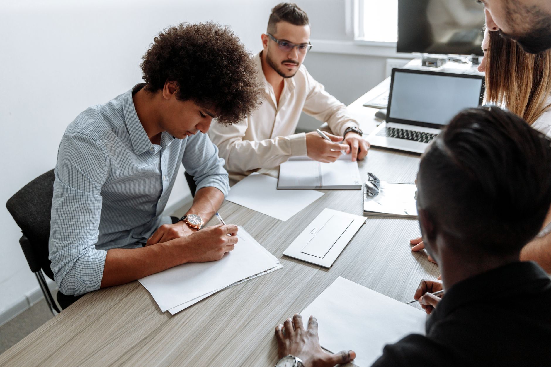 Small business team gathered around a table reviewing sales reports on laptops