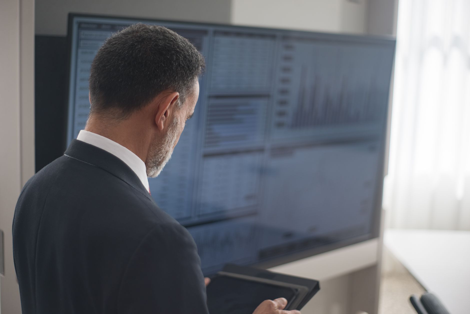 Modern technology company office interior with financial charts displayed on screens