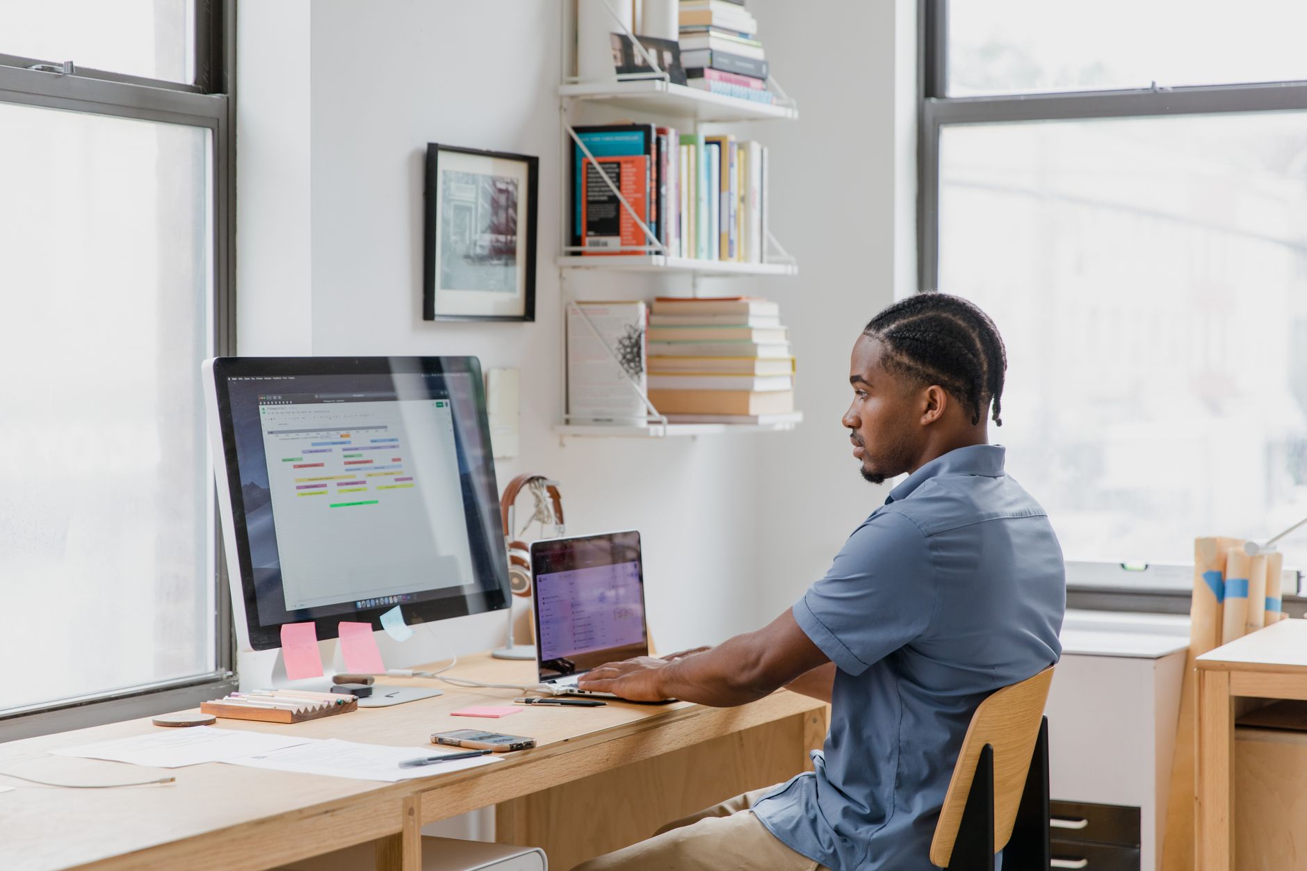 Professional at a desk working on multiple screens displaying project tracking and task management tools