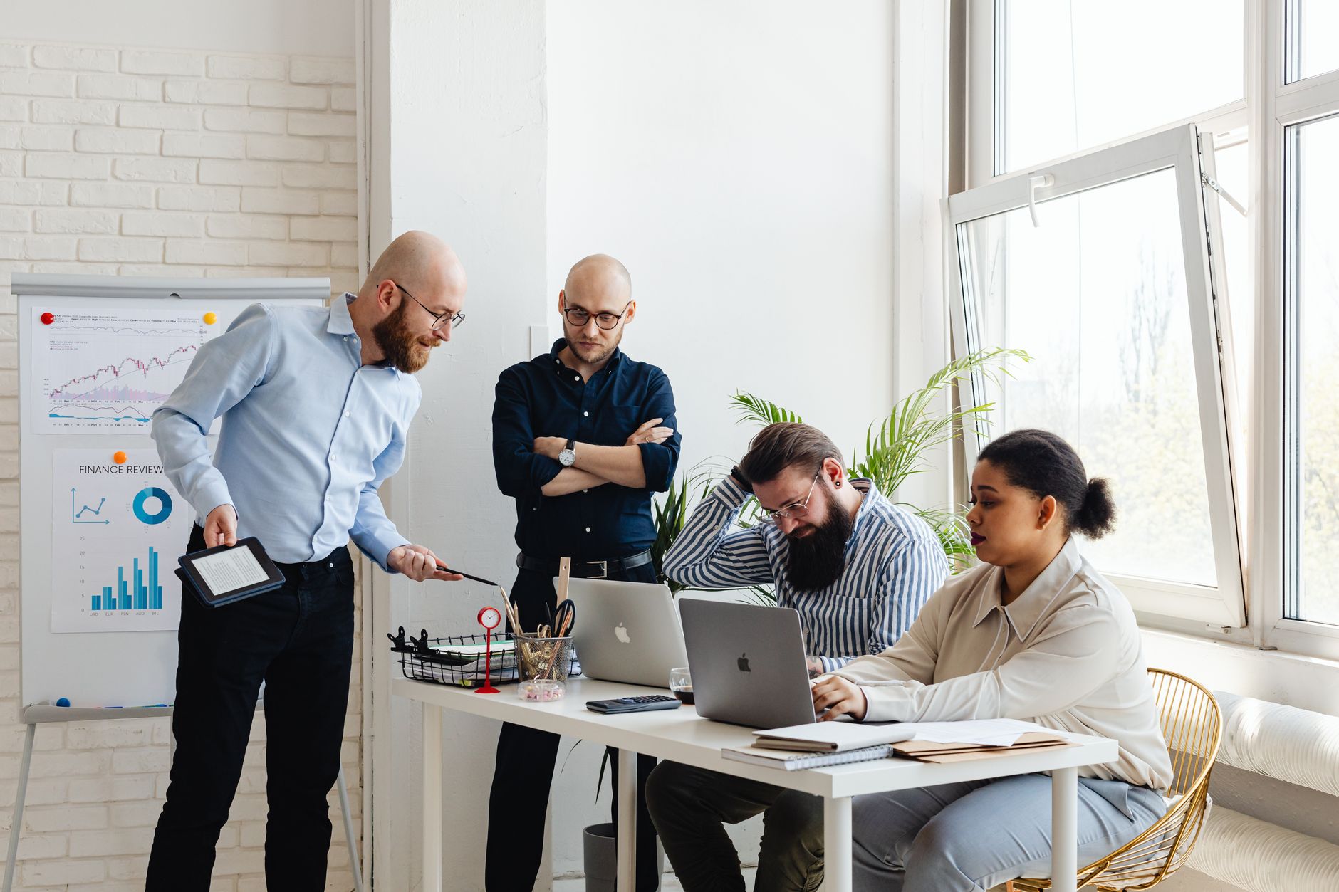 A group of office employees collaborating around a table with laptops and presentation materials